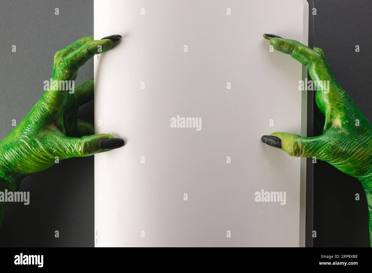 Lancette di mostri verdi che reggono il notebook con spazio per la copia su sfondo grigio Foto Stock