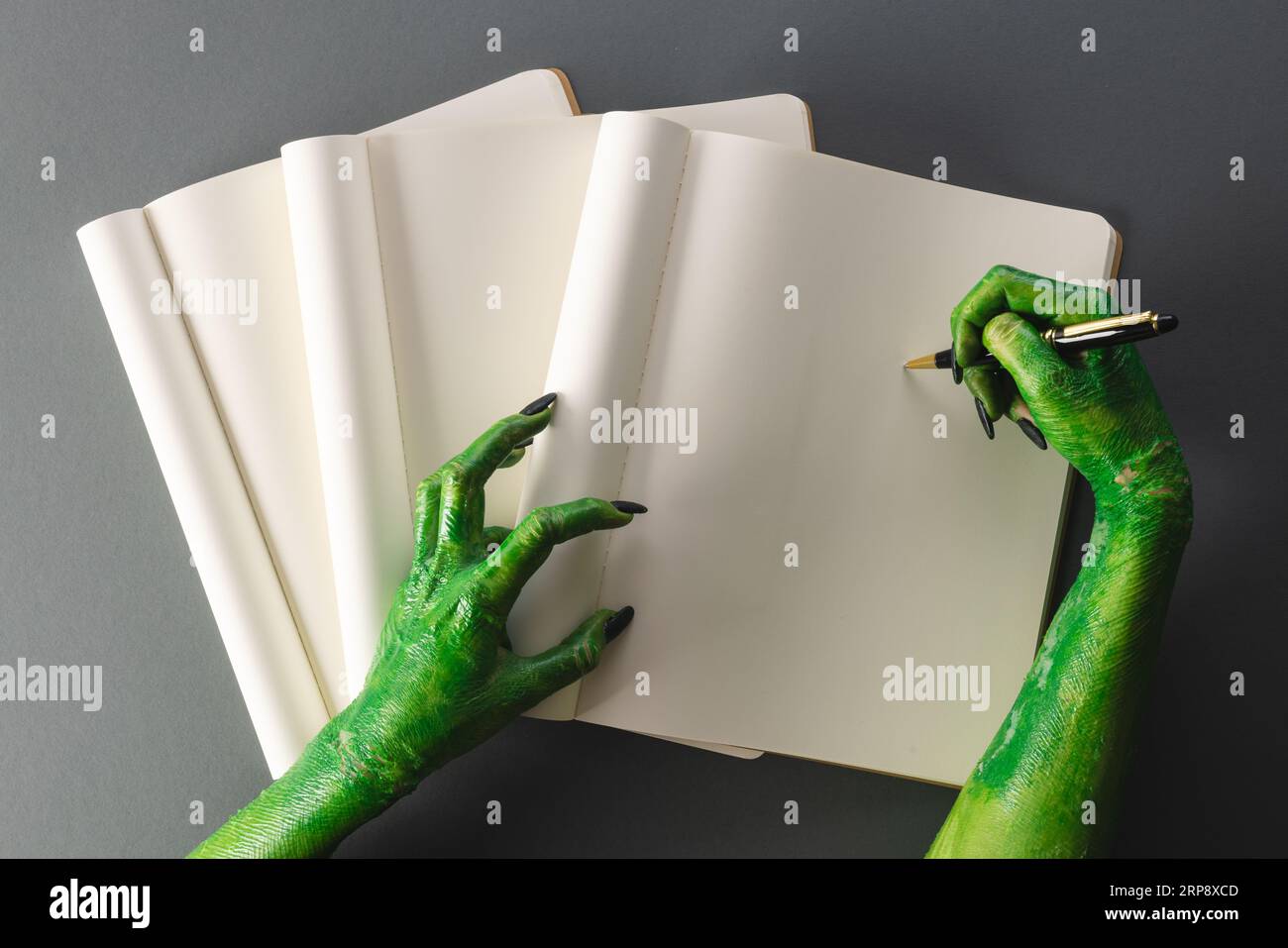 Le mani dei mostri verdi scrivono su un notebook con spazio per la copia su sfondo grigio Foto Stock