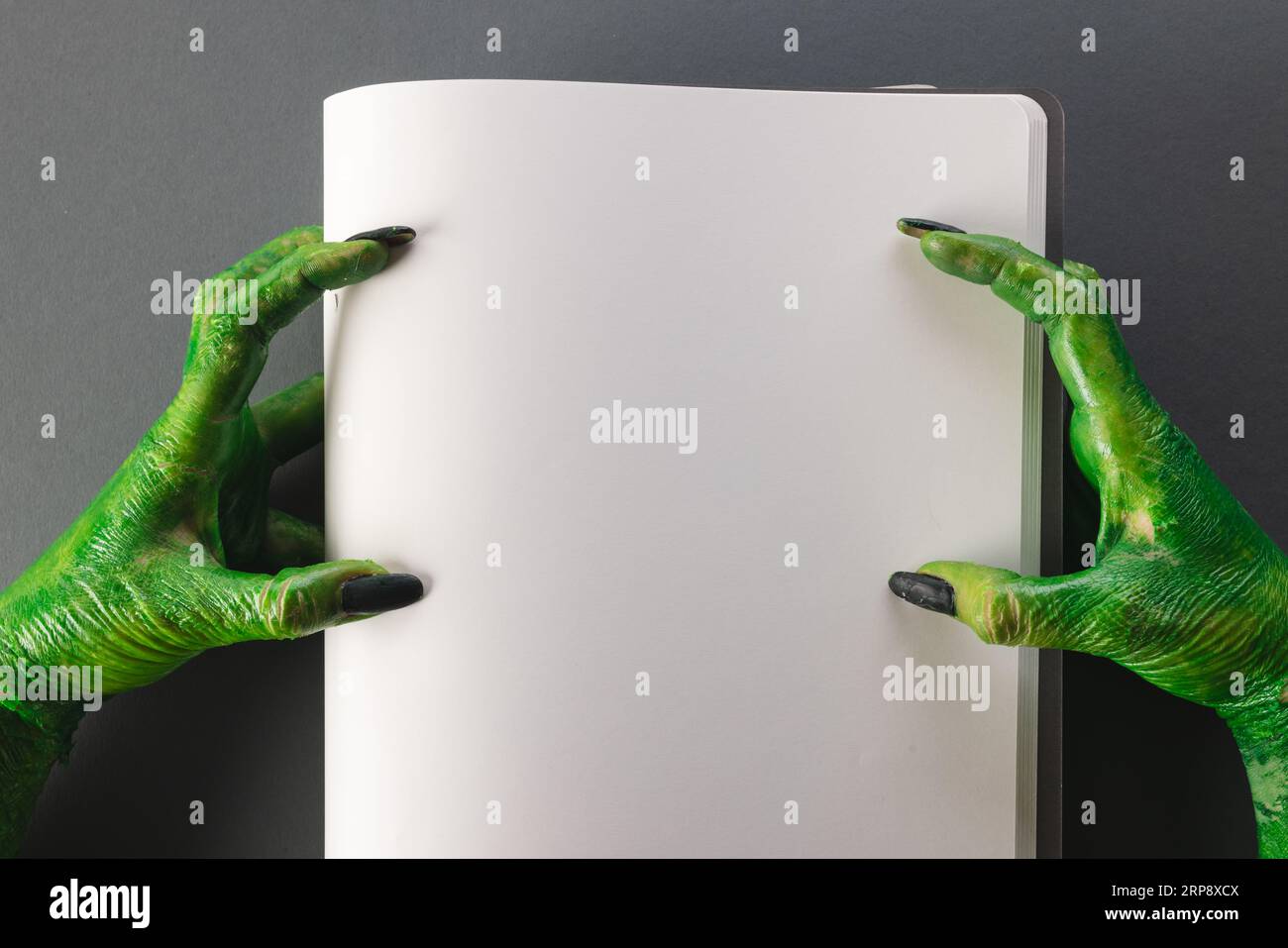 Lancette di mostri verdi che reggono il notebook con spazio per la copia su sfondo grigio Foto Stock