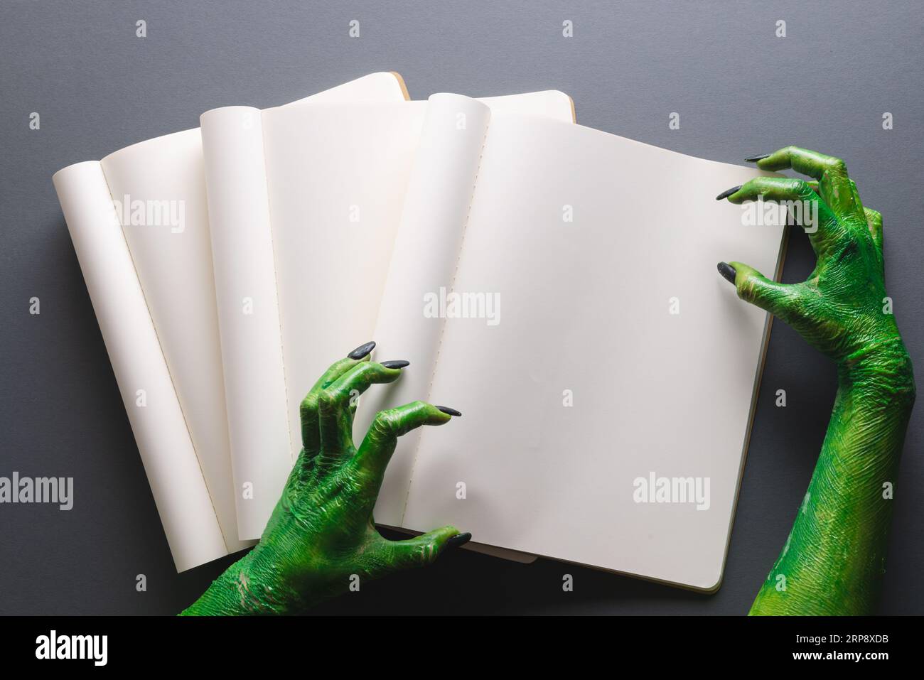 Lancette di mostri verdi che fanno gesto di presa sul notebook con spazio per la copia su sfondo grigio Foto Stock