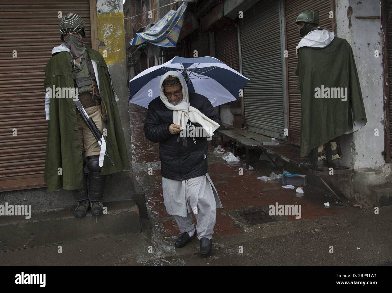 (190320) -- SRINAGAR, 20 marzo 2019 (Xinhua) -- Un uomo cammina davanti ai soldati paramilitari indiani in un mercato chiuso durante il blocco della sicurezza a Srinagar, la capitale estiva del Kashmir controllato dagli indiani, 20 marzo 2019. La vita normale nelle aree a maggioranza musulmana del Kashmir restive controllato dall'India mercoledì è rimasta colpita a causa di uno sciopero sulla morte custode di un insegnante di scuola. L'appello allo sciopero è stato dato dai gruppi separatisti della regione sotto la bandiera della Joint Resistance Leadership (JRL). (Xinhua/Javed Dar) KASHMIR-SRINAGAR-LOCKDOWN PUBLICATIONxNOTxINxCHN Foto Stock