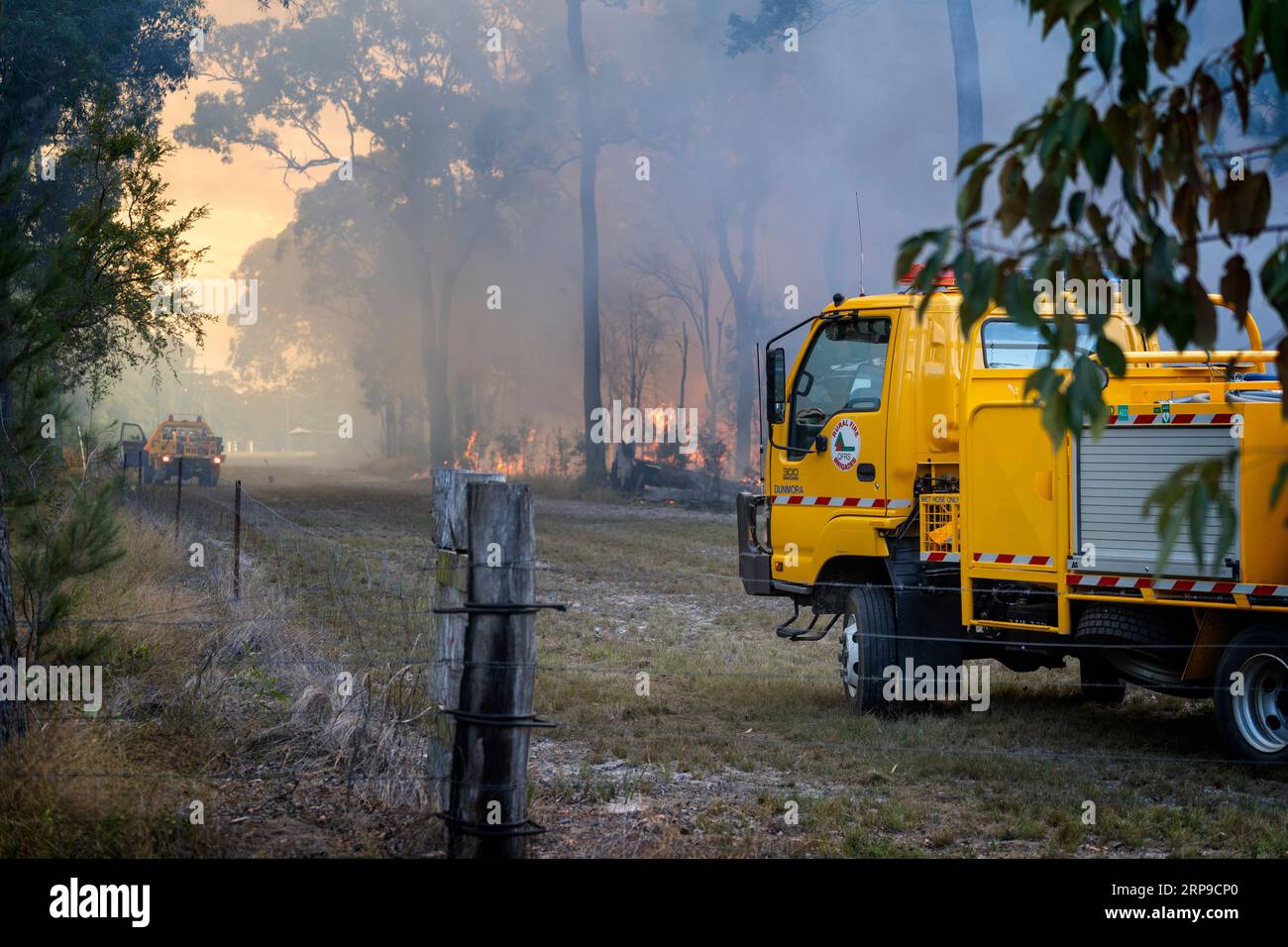 Apparecchiatura per vigili del fuoco rurale gialla con fiamme in background per la gestione di una combustione controllata. Maryborough, Queensland, Australia Foto Stock