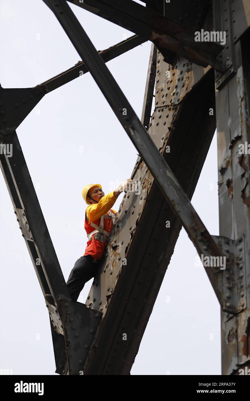 (190423) -- CHONGQING, 23 aprile 2019 (Xinhua) -- Tang Jinhua controlla la ruggine sul precedente ponte ferroviario del fiume Baishatuo Yangtze a Jiangjin, nel comune di Chongqing della Cina sud-occidentale, 23 aprile 2019. Il precedente ponte ferroviario del fiume Baishatuo Yangtze, completato nel 1959, cesserà il servizio dopo il 24 aprile. Dopo quel giorno, tutti i treni percorreranno il nuovo ponte ferroviario a due piani con capriata in acciaio. Il nuovo ponte ha 4 binari sul ponte superiore per treni passeggeri con una velocità prevista di 200 chilometri all'ora e 2 binari sul ponte inferiore per treni merci con una velocità prevista di 12 Foto Stock