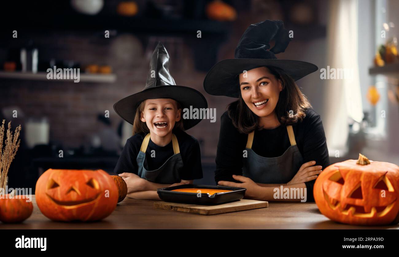 Madre e sua figlia si divertono a casa. Happy Family in preparazione per Halloween. Mamma e bambino cucinano piatti festosi in cucina. Foto Stock