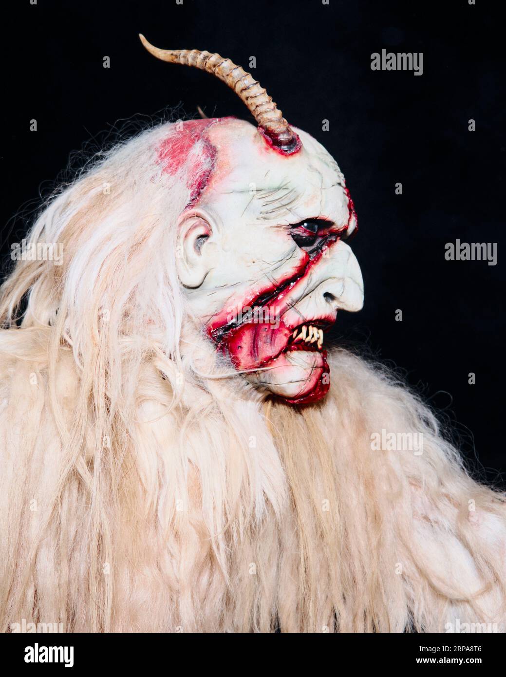 Una creatura bianca mitica con corna e capelli lunghi che guardano lateralmente con un'espressione premurosa Foto Stock