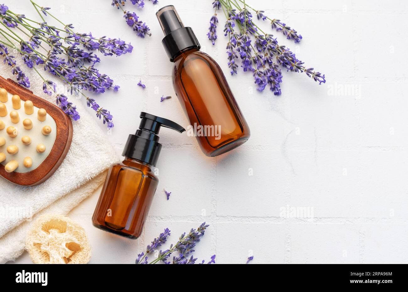 Vasca idromassaggio con lavanda. Sale di lavanda, olio essenziale naturale, spazzole per massaggi e lavanda fresca su fondo di piastrelle bianche. Foto Stock