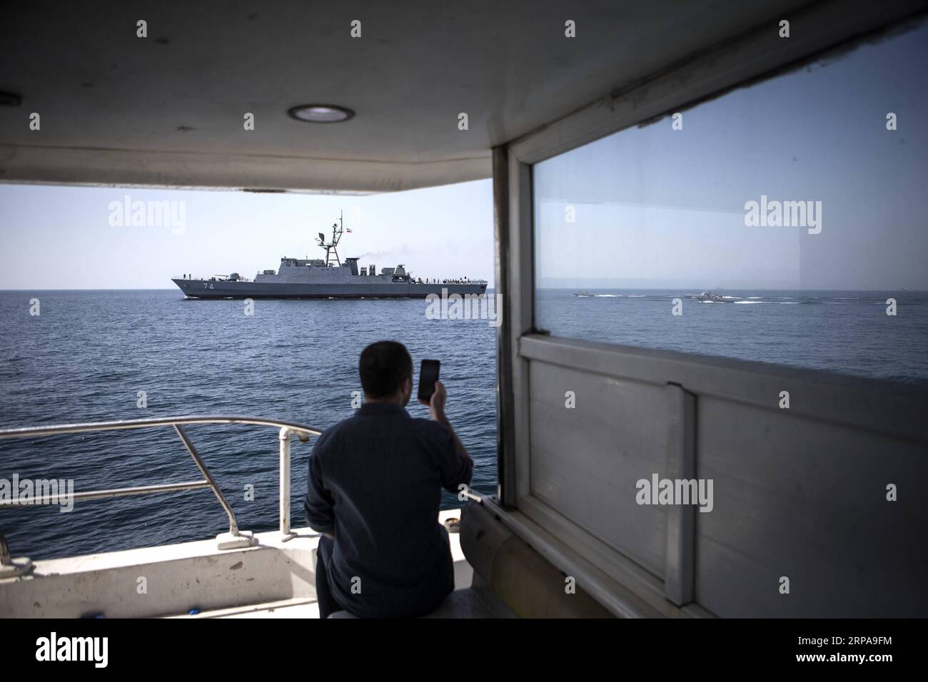 (190430) -- HORMUZ, 30 aprile 2019 -- Un uomo fotografa una nave da guerra iraniana nello stretto di Hormuz, nell'Iran meridionale, 30 aprile 2019. Domenica il comandante militare iraniano ha dichiarato che la repubblica islamica non intende chiudere lo stretto di Hormuz per il trasporto marittimo internazionale. Teheran vuole che lo stretto di Hormuz rimanga aperto con una sicurezza sostenuta, il capo di stato maggiore delle forze armate iraniane il maggiore generale Hossein Baqeri è stato citato dall'agenzia di stampa Tasnim. IRAN-STRETTO DI HORMUZ-SICUREZZA MILITARE AHMADXHALABISAZ PUBLICATIONXNOTXINXCHN Foto Stock