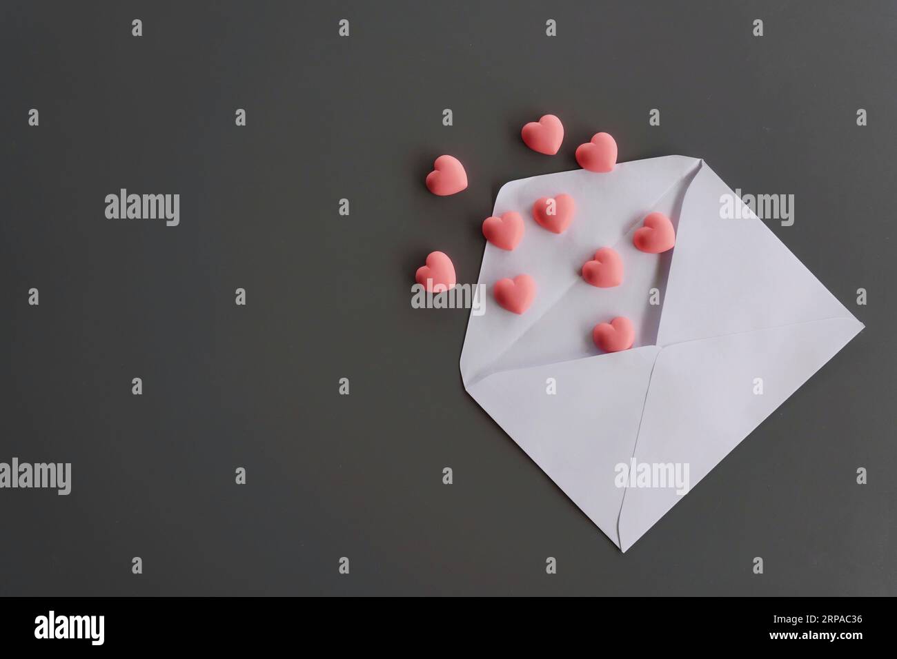 Cuori rosa e busta su sfondo nero, piano con spazio per la copia. Lettera d'amore, idea di san valentino Foto Stock