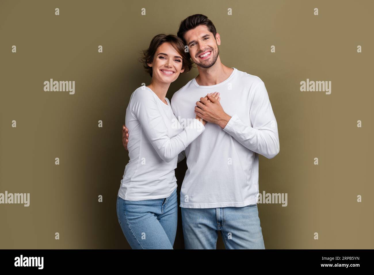 Foto di una coppia positiva e dolce che indossa abiti bianchi Godetevi del tempo insieme anniversario luna di miele isolata su sfondo marrone Foto Stock