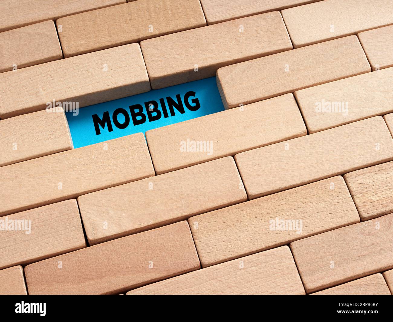 Per rivelare il concetto di mobbing nascosto. La parola mobbing circondata da blocchi di legno. Foto Stock