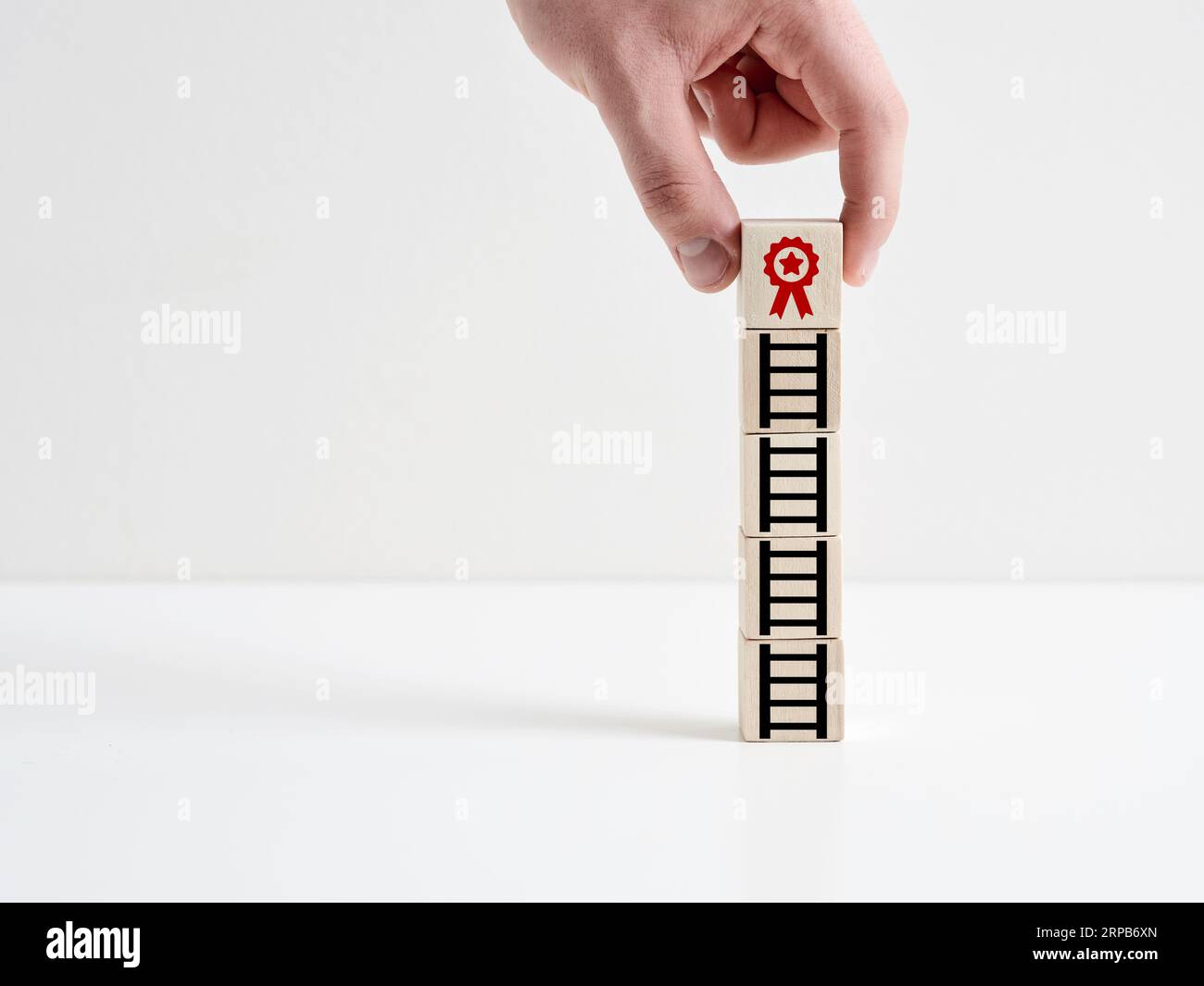 Vincere un premio. La strada per il successo nel business. Ottenere una certificazione di qualità. Servizi aziendali o prodotti eccellenti. La mano posiziona un cubo di legno Foto Stock