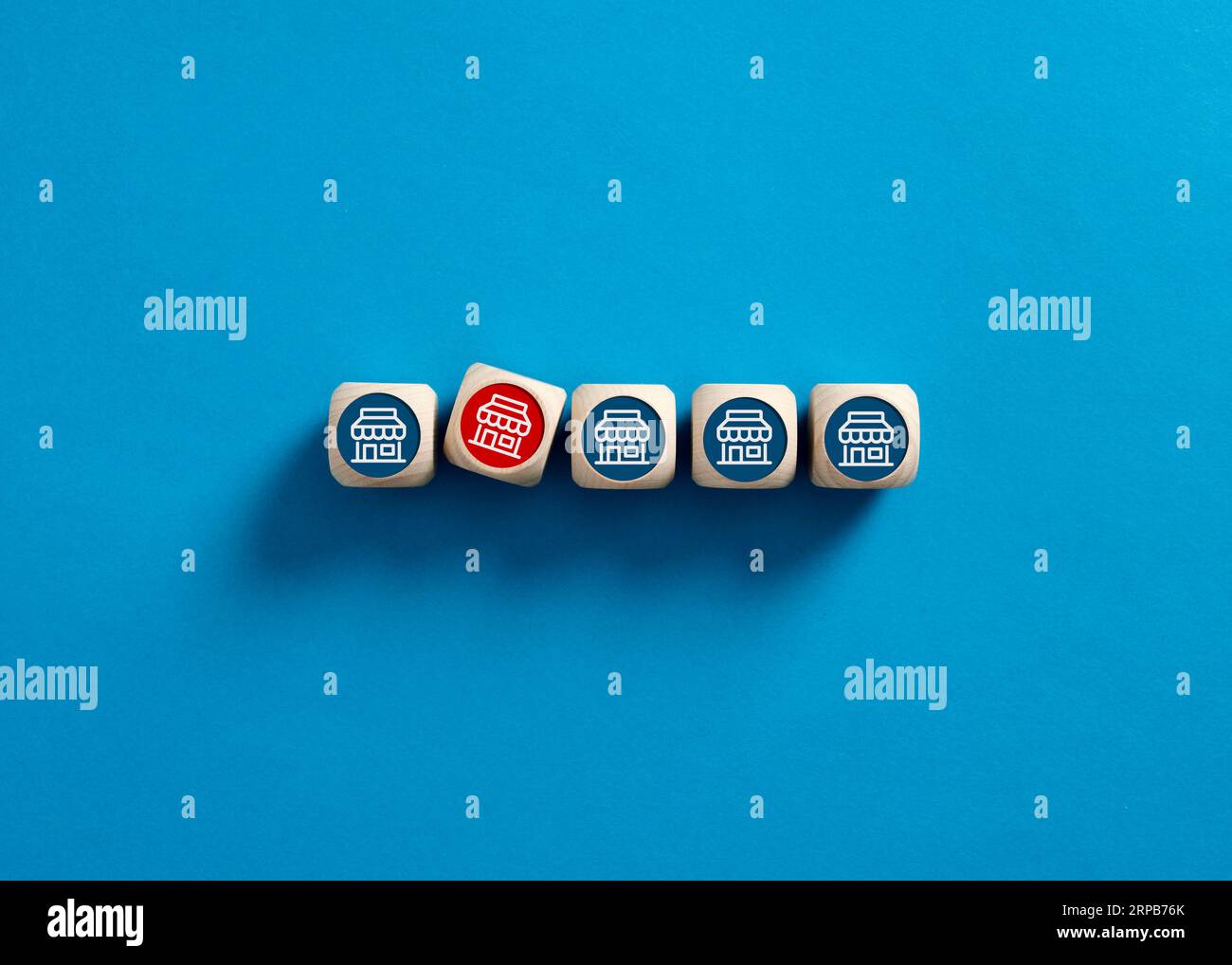 Negozio in franchising non redditizio e senza successo. Sistema di franchising incompetente. Un deposito rosso tra quelli blu su cubetti di legno. Foto Stock