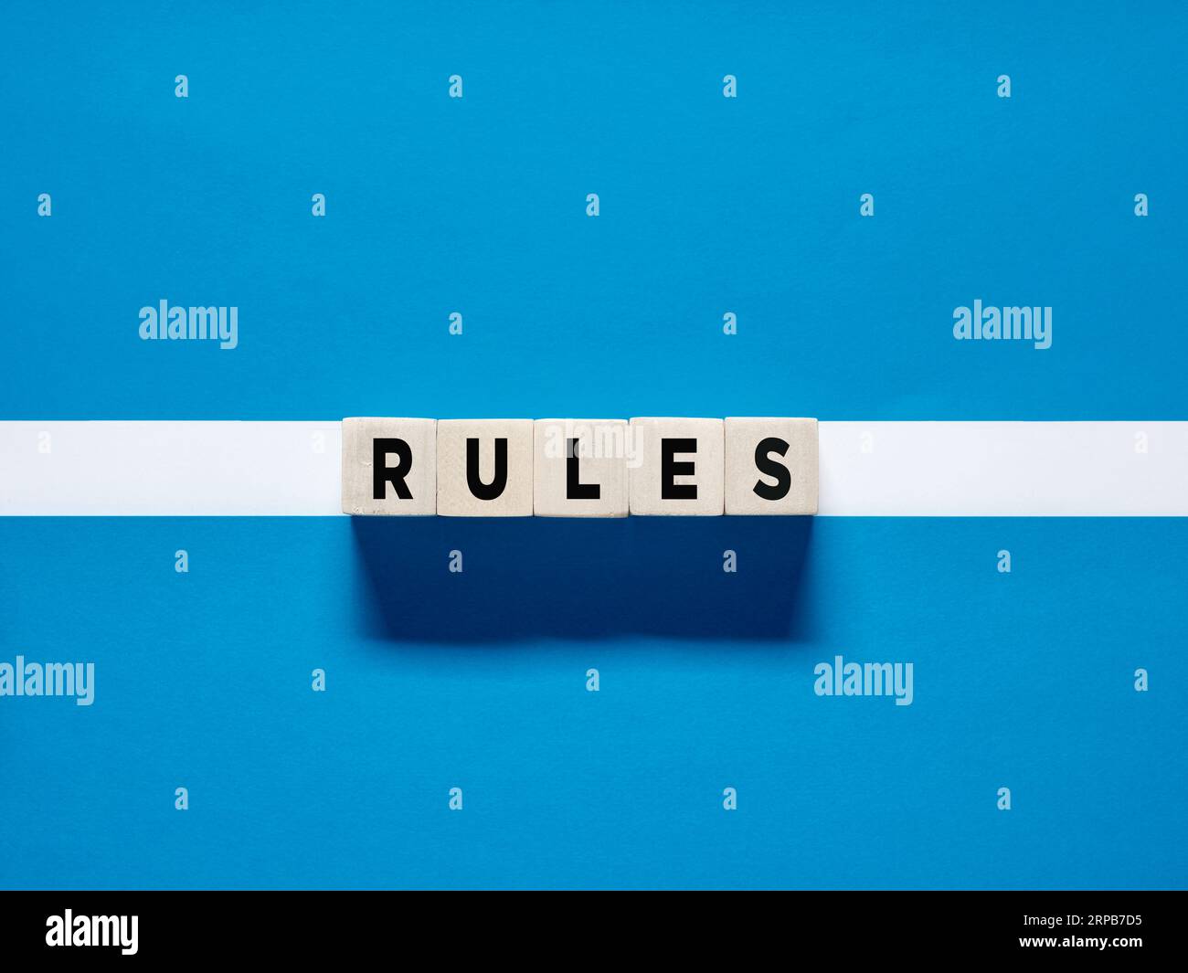 La parola regola i cubi di legno su sfondo bianco blu. Le procedure, gli standard e i principi che guidano le persone in qualsiasi contesto. Foto Stock