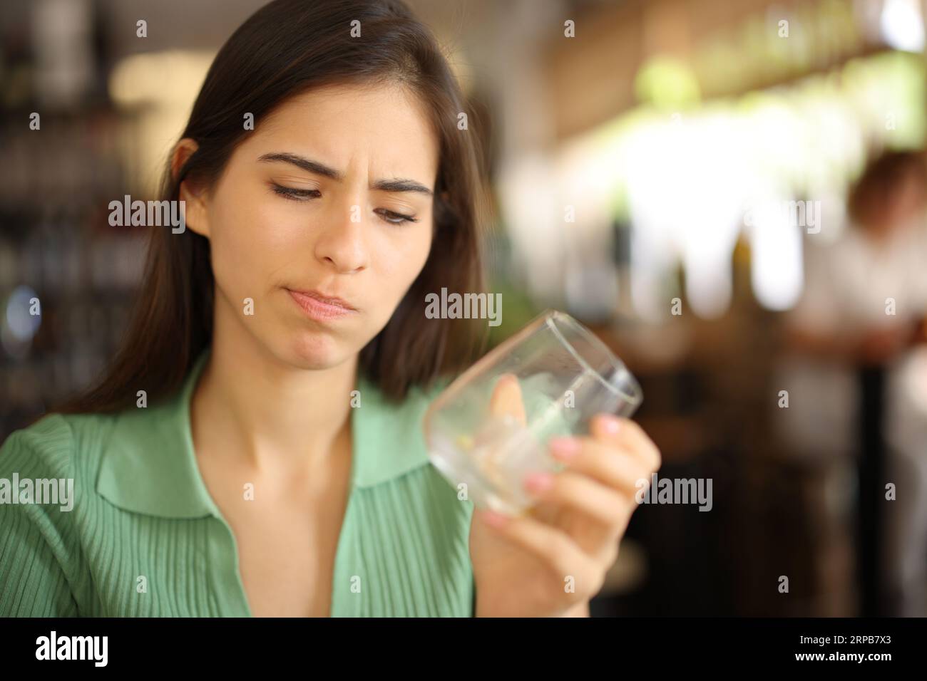 Donna delusa che guarda un bicchiere vuoto all'interno di un bar Foto Stock