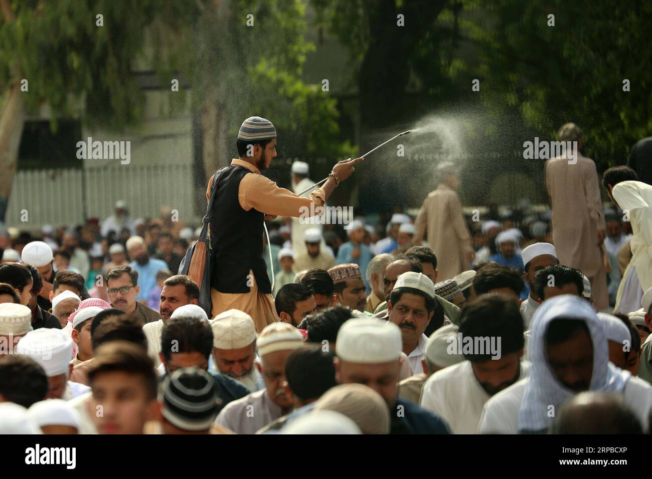 (190605) -- RAWALPINDI, 5 giugno 2019 -- Un volontario spruzza acqua con il caldo mentre i musulmani offrono preghiere durante Eid al-Fitr all'Eidgah Sharif a Rawalpindi, Pakistan, 5 giugno 2019. ) PAKISTAN-RAWALPINDI-EID AL-FITR-CELEBRATION AHMADXKAMAL PUBLICATIONXNOTXINXCHN Foto Stock