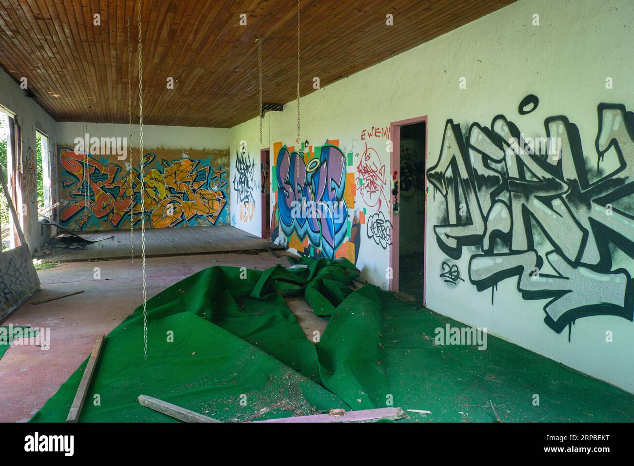 Interno di una casa abbandonata con cartellini, catene e tappeto verde. Foto Stock
