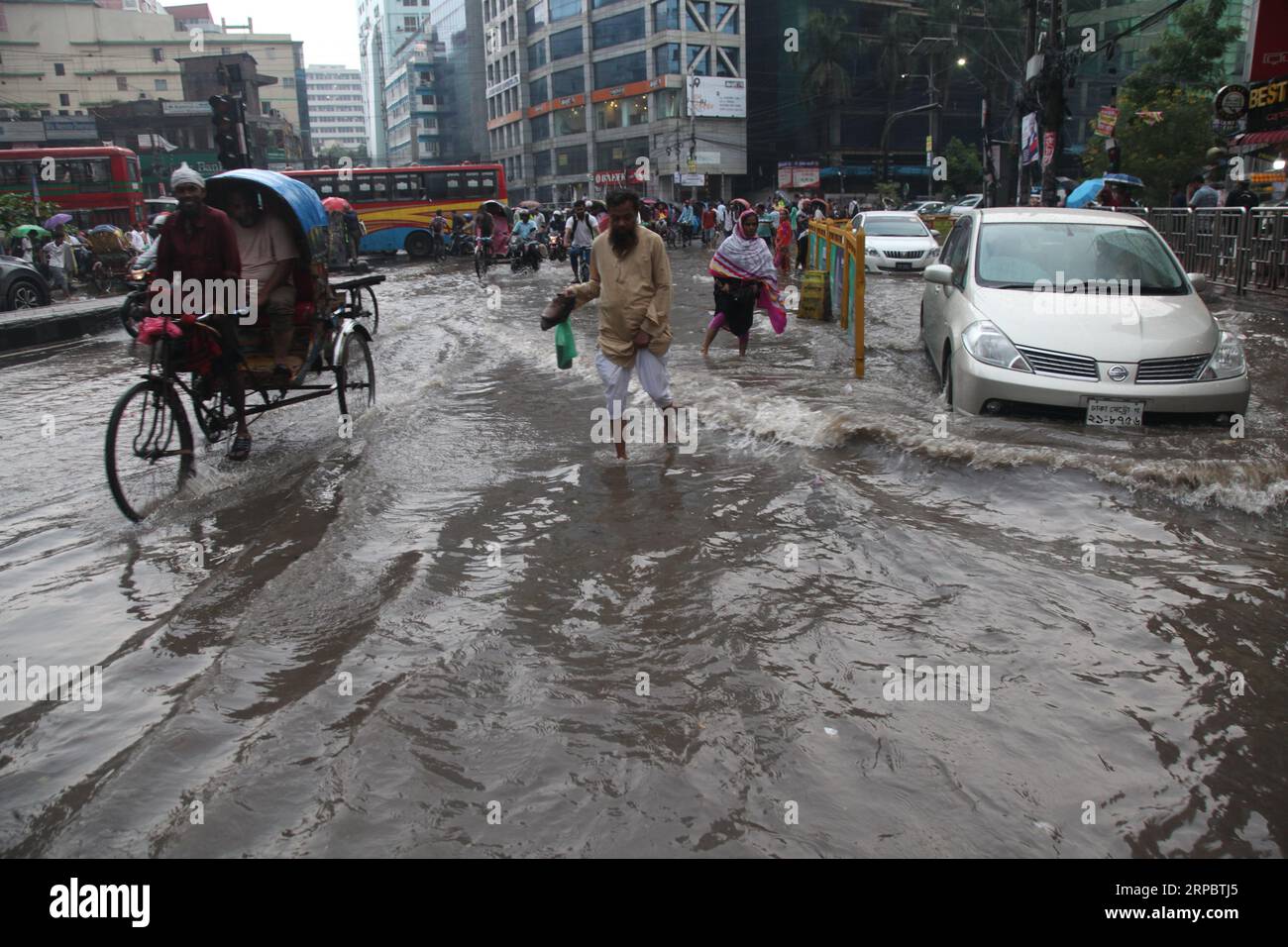 Dhaka, Bangladesh. Il 9 agosto 2023.. I bengalesi attraversano una strada allagata a Dacca, Bangladesh. Il disboscamento delle acque è diventato un problema perenne f Foto Stock