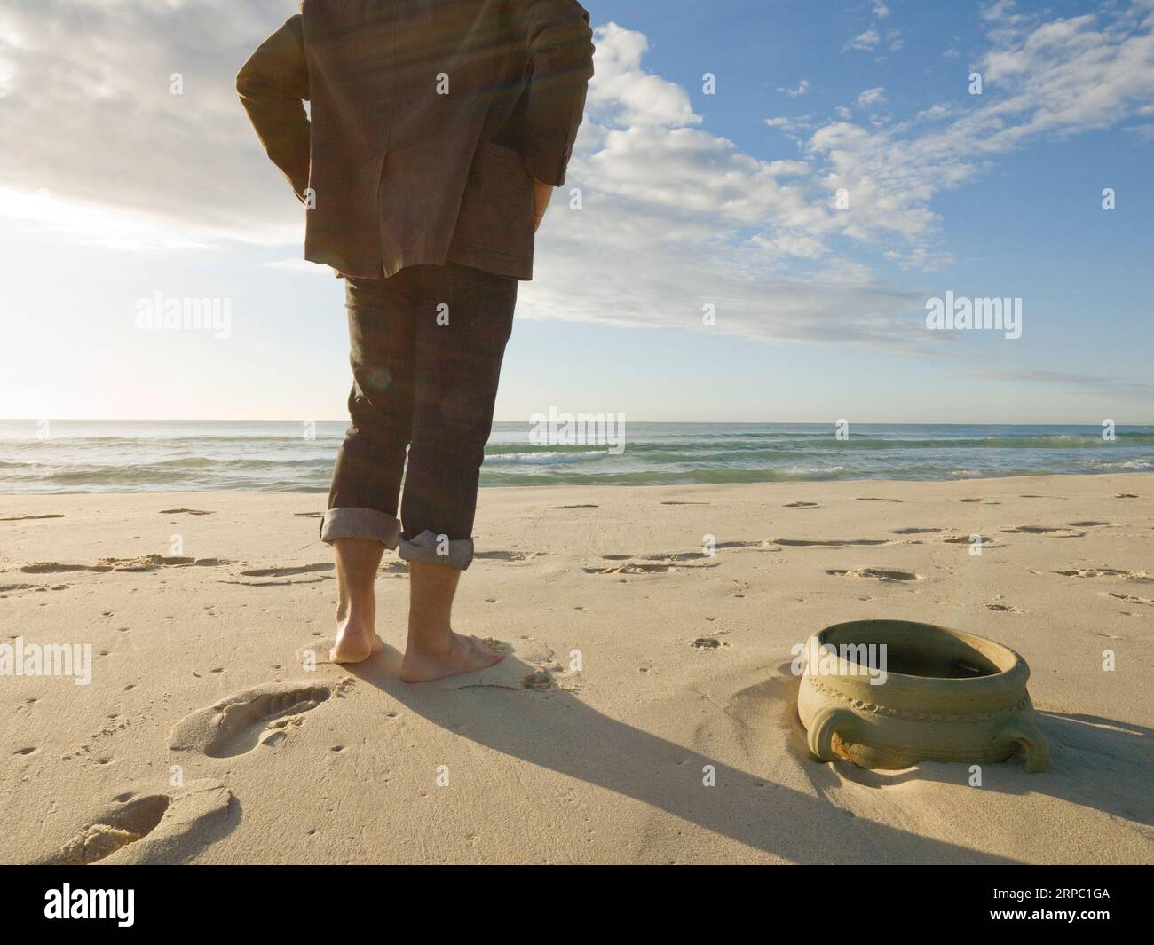 Dettaglio dei piedi e dell'urna di argilla sepolta nella sabbia vicino all'oceano Foto Stock