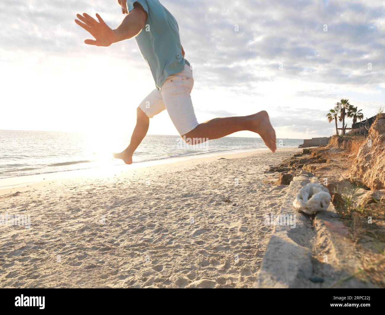 Un uomo maturo salta sulla spiaggia all'alba Foto Stock