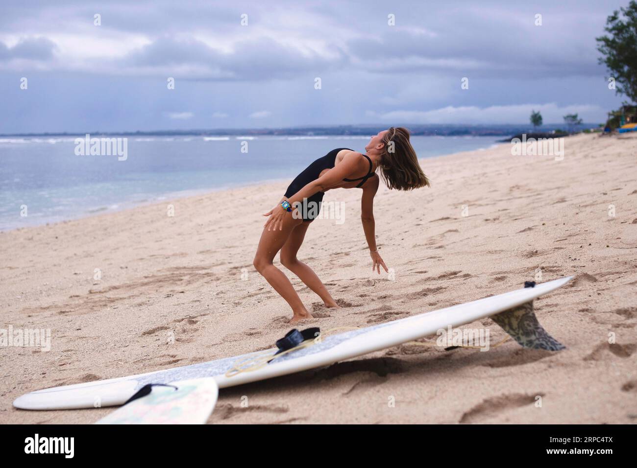 Un surfista esegue una curvatura posteriore durante il riscaldamento prima di fare surf Foto Stock