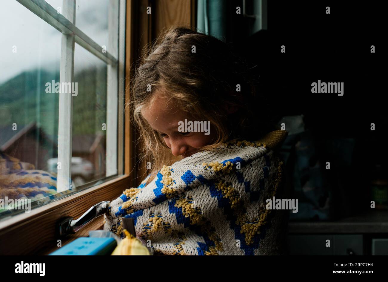 ragazza in un accogliente saltatore norvegese che guarda fuori dal finestrino di una cabina Foto Stock
