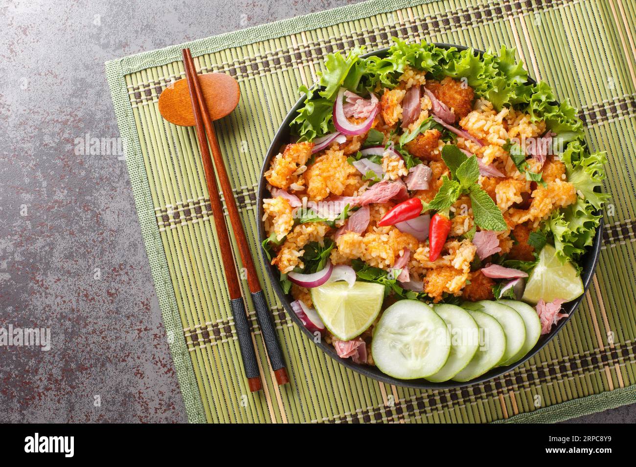 Insalata di maiale fermentato e riso croccante in Laos o primo piano di Yam Naem Khao sul piatto sul tavolo. Vista superiore orizzontale dall'alto Foto Stock