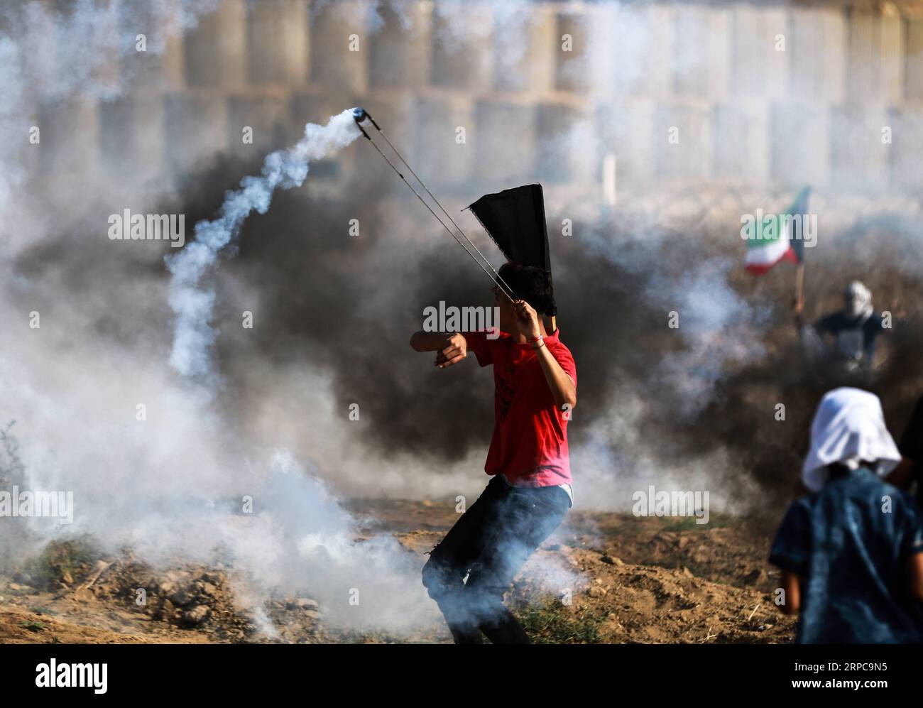 (190628) -- GAZA, 28 giugno 2019 (Xinhua) -- Un manifestante palestinese usa una fionda per respingere una tanica di gas lacrimogeni sparata dalle truppe israeliane durante gli scontri sul confine tra Gaza e Israele, a est del campo profughi di al-Bureij nella Striscia di Gaza centrale, 28 giugno 2019. Almeno 50 palestinesi sono rimasti feriti venerdì negli scontri tra decine di manifestanti e soldati israeliani di stanza al confine tra la Striscia di Gaza orientale e Israele. (Xinhua/Yasser Qudih) MIDEAST-GAZA-CLASHES PUBLICATIONxNOTxINxCHN Foto Stock