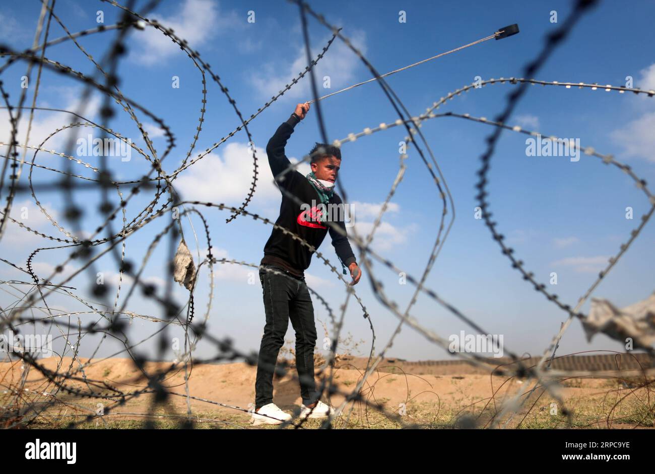 (1906289) - PECHINO, 29 giugno 2019 - Un manifestante palestinese usa una fionda per lanciare pietre contro le truppe israeliane durante gli scontri sul confine tra Gaza e Israele, a est del campo profughi di al-Bureij nella Striscia di Gaza centrale, 28 giugno 2019. Almeno 50 palestinesi sono rimasti feriti venerdì negli scontri tra dozzine di manifestanti e soldati israeliani di stanza al confine tra la Striscia di Gaza orientale e Israele. ) XINHUA FOTO DEL GIORNO YasserxQudih PUBLICATIONxNOTxINxCHN Foto Stock