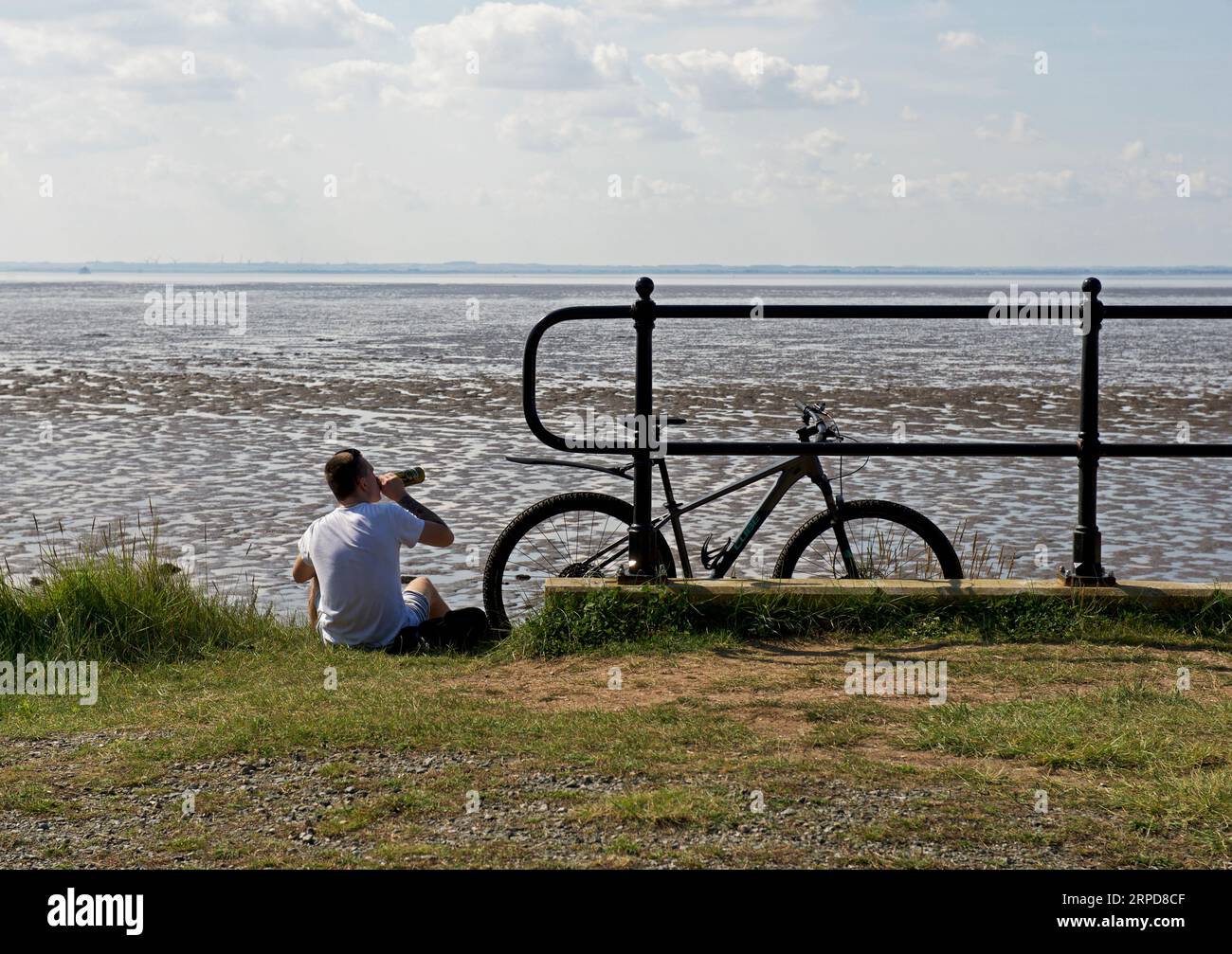 Giovane seduto, guardando l'estuario dell'Humber, a Kilnsea, Holderness, East Yorkshire, Inghilterra, Regno Unito Foto Stock