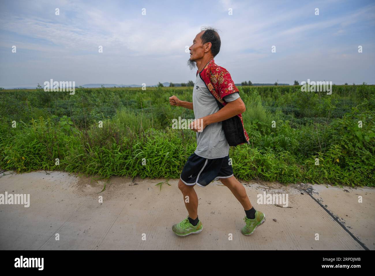 (190806) -- CHANGCHUN, 6 agosto 2019 -- alto e sottile, con una barba ovvia e una sorprendente giacca rossa imbottita in cotone fiorito, Xi Zhanyu, 63 anni, ha tagliato una figura distintiva correndo nel campo nel villaggio rurale di Taku, vicino alla città nordorientale della Cina di Changchun. I vestiti appartenevano alla mia defunta moglie Xia Shuyun. Volevo correre con lei. XI ha detto. Nel 2015, a Xia fu diagnosticato un cancro ai polmoni. Quando è morta, Xia ha sentito che aveva ancora molto da fare. Poi ho iniziato a correre per vedere se mi avrebbe dato conforto, ha detto. Da quel momento in poi, ogni giorno, con la pioggia o il sole, gli abitanti del villaggio vedranno Xi correre fr Foto Stock