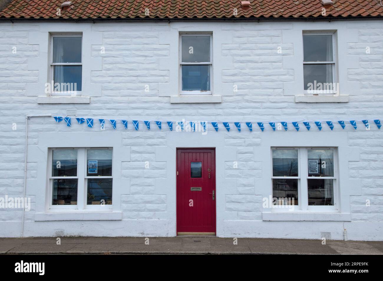 Saltire, la St Andrew's Cross, la bandiera nazionale di Scozia appesa come un nastro di bandiere sul fronte di una casa bianca. Cockenzie e Port Seton East Lothian, Scozia 2023. UK HOMER SYKES Foto Stock