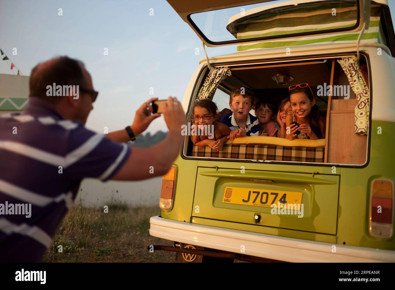 Un maschio adulto scatta una foto di cinque bambini sul retro di un camper. Foto Stock