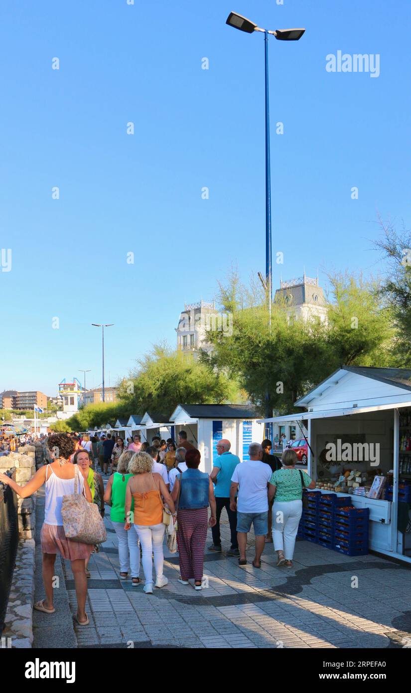 Fila di bancarelle del mercato con persone che camminano lungo la passeggiata durante l'evento Bano de Olas Sardinero Santander Cantabria Spagna Foto Stock