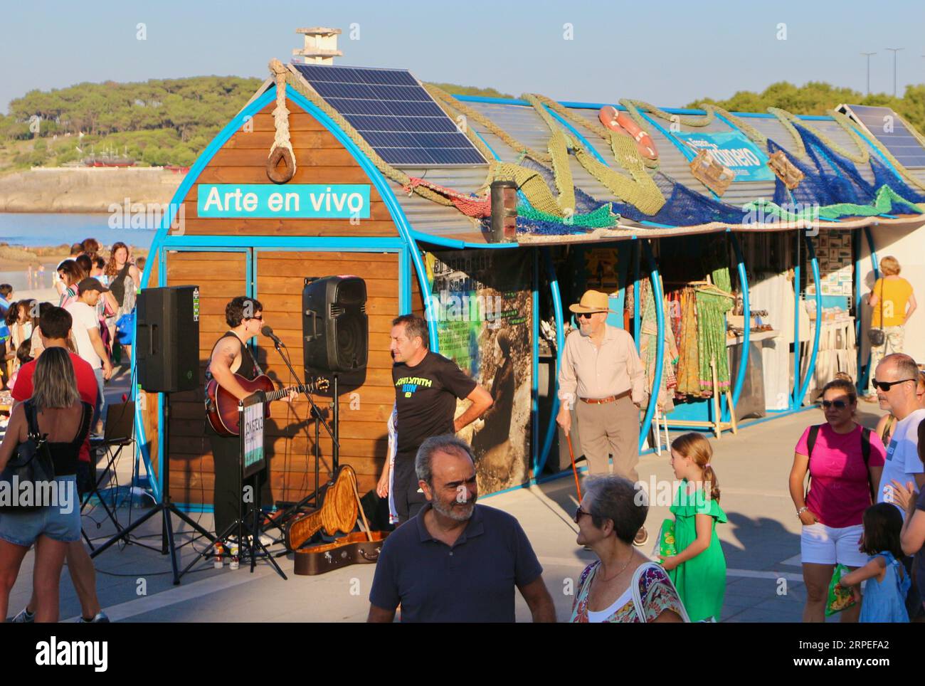 Fila di bancarelle del mercato con gente che naviga lungo il lungomare e il busker Gon Estevz Bano de Olas evento Sardinero Santander Cantabria Spagna Foto Stock