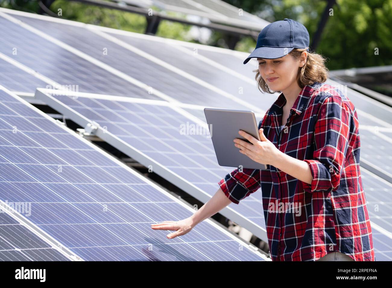 Donna con un tablet digitale sullo sfondo di una centrale elettrica solare mobile.. Foto Stock