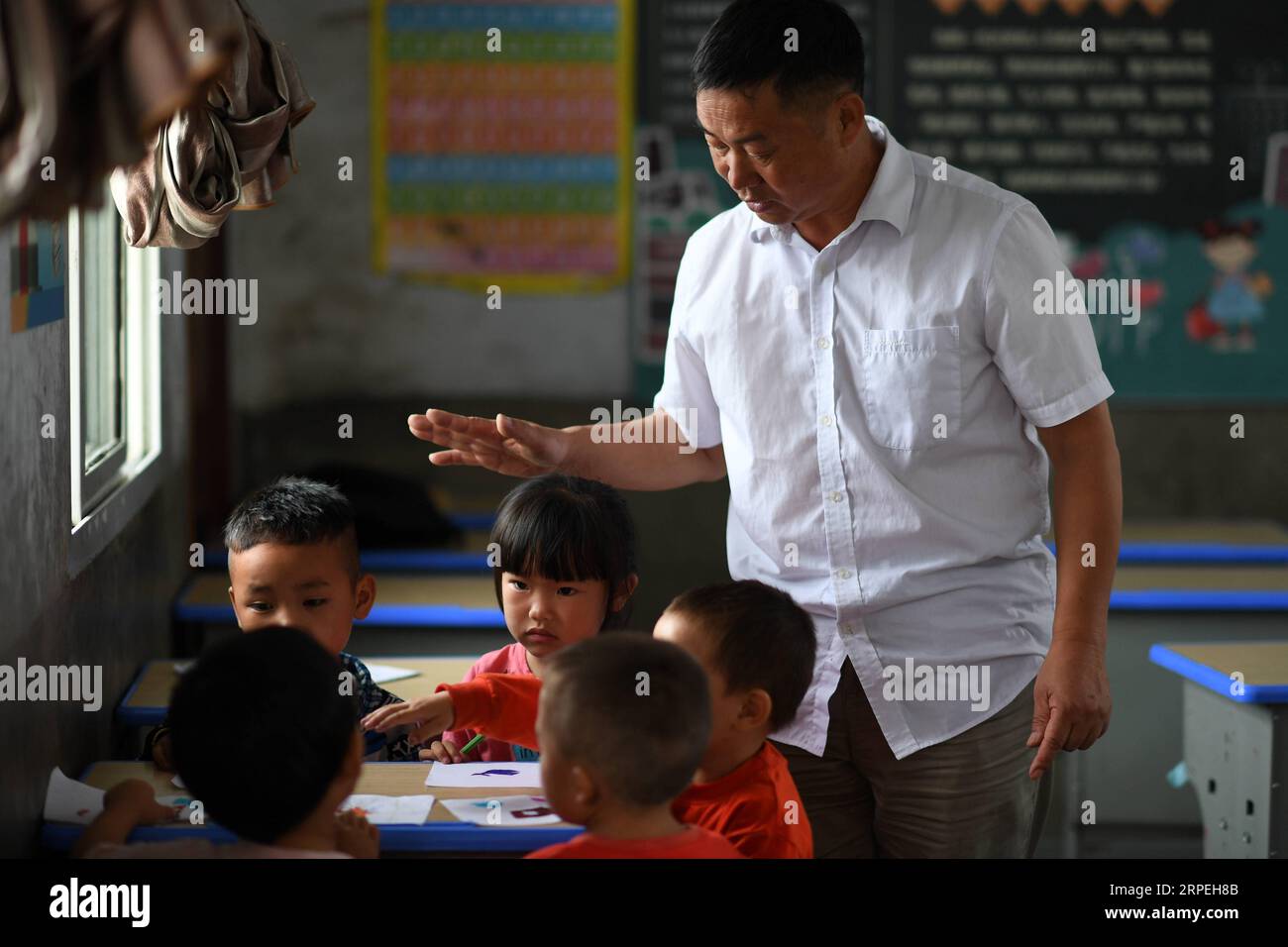 (190829) -- GUIYANG, 29 agosto 2019 -- Wu Guoxian insegna disegno agli studenti prescolastici della Gugang Primary School nel villaggio di Liuguang nella contea di Longli nella prefettura autonoma di Bouyei-Miao di Qiannan, nella provincia di Guizhou della Cina sud-occidentale, 27 agosto 2019. Situata nel profondo delle montagne, la scuola primaria Gugang nel villaggio di Liuguang ha accolto sei studenti dell'età prescolare e quattro studenti di prima elementare quando il nuovo semestre è iniziato lunedì. Saranno insegnati da Wu Guoxian, l'unico insegnante di scuola qui. Wu, 53 anni, ha lavorato nella scuola per 36 anni da quando si è diplomato in una scuola media nel 1983. La scuola ha Foto Stock