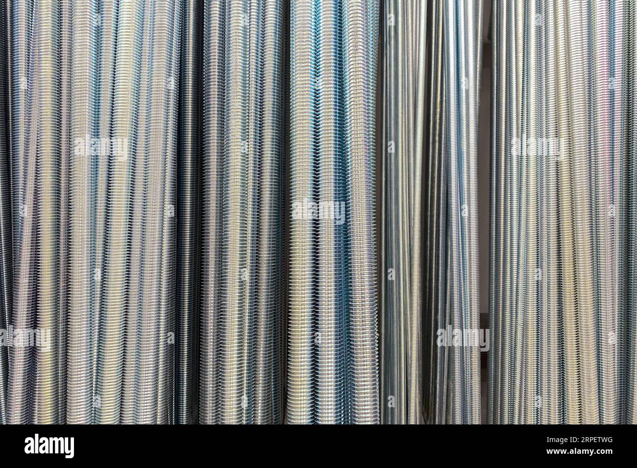 Prigionieri filettati. Asta in metallo zincato con filettature per l'intera lunghezza. Prigionieri di diverso spessore in un negozio di ferramenta. Foto Stock