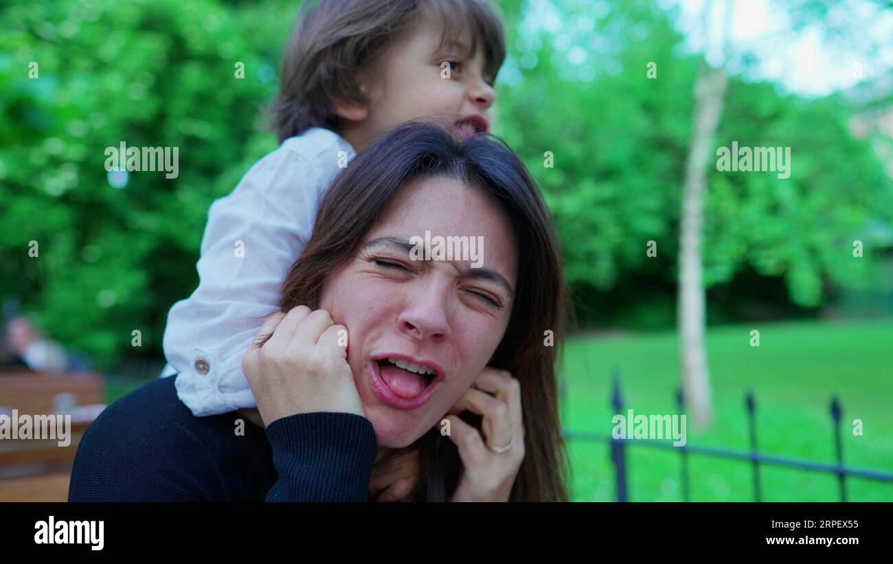 Un ragazzino incauto che soffoca la mamma mentre gioca. Il ragazzo non conosce i limiti del gioco, la madre sconvolta, la vita reale Foto Stock