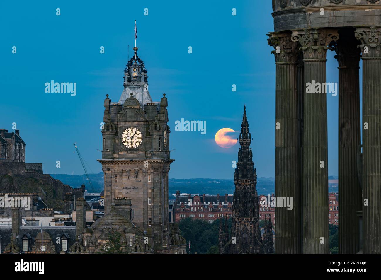 Skyline della città con una superluna blu sulla torre dell'orologio Balmoral, monumento Scott da Calton Hill con monumento Dugald Stewart, Edimburgo, Scozia, Regno Unito Foto Stock