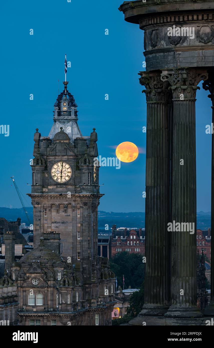 Skyline della città con una superluna blu sulla torre dell'orologio Balmoral, monumento Scott, Edimburgo, Scozia, Regno Unito Foto Stock