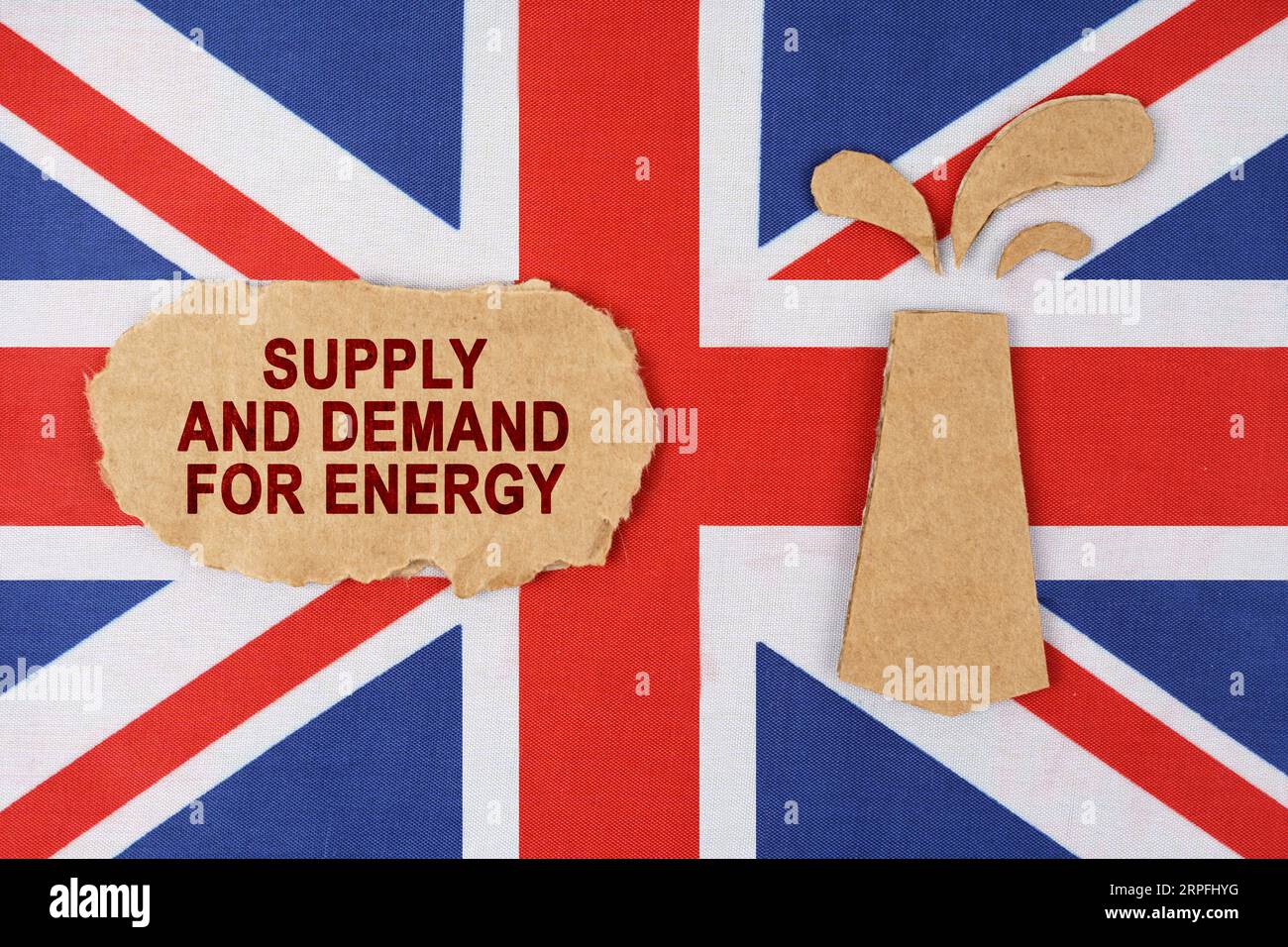 Sulla bandiera della Gran Bretagna c'è una piattaforma petrolifera tagliata di cartone e un cartello con l'iscrizione - offerta e domanda di energia. Foto Stock