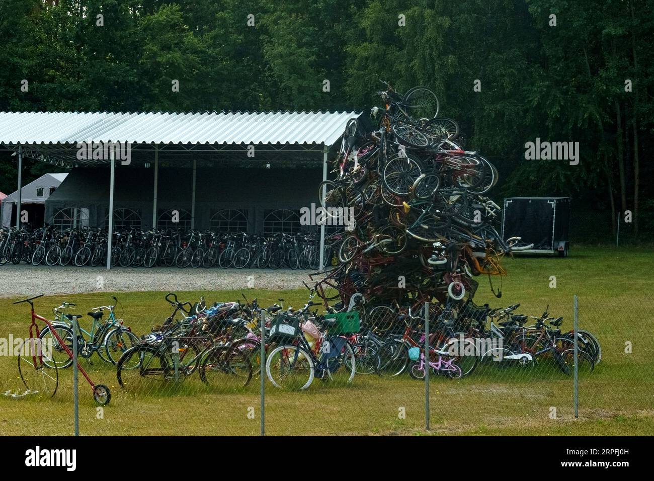 Una montagna di vecchie biciclette si trova in un'area verde. Foto Stock