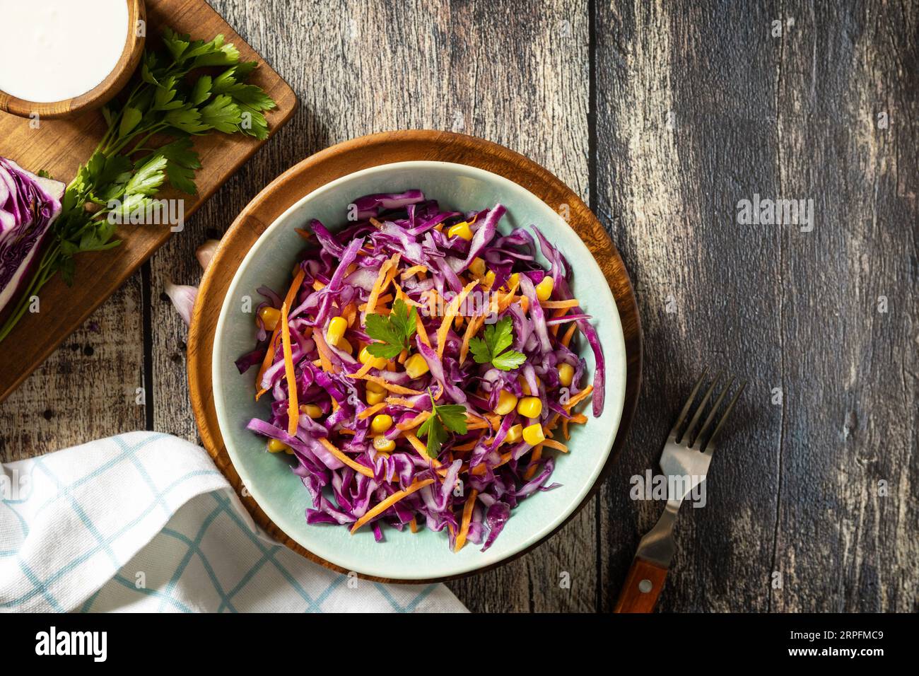 Concetto di cibo vegano, cibo sano. Insalata di cavolo viola fatta in casa con mais, carote e yogurt greco su un tavolo rustico. Vista dall'alto. Copia spazio. Foto Stock