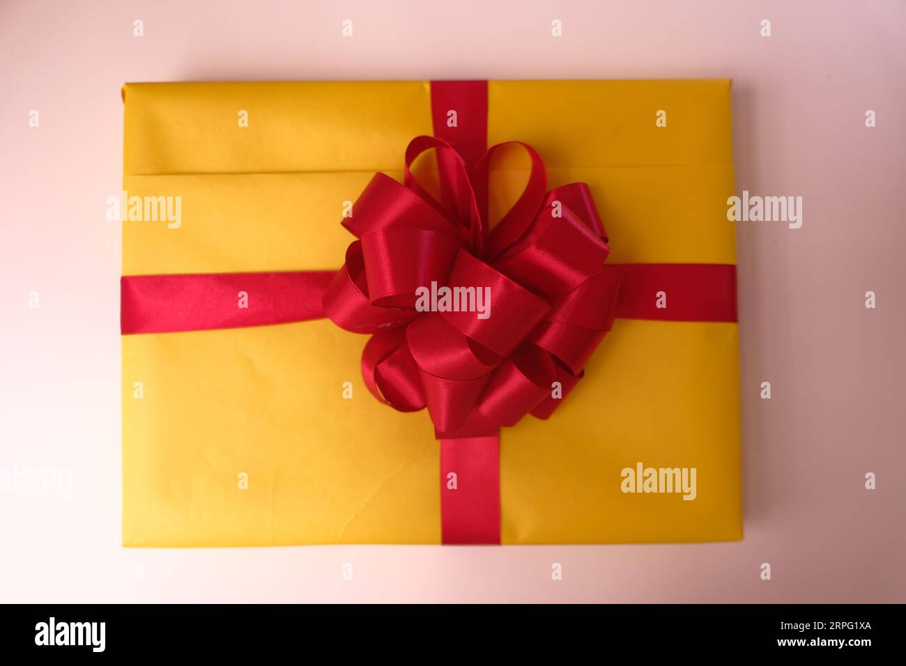 Confezione regalo gialla con nastro rosso Foto Stock
