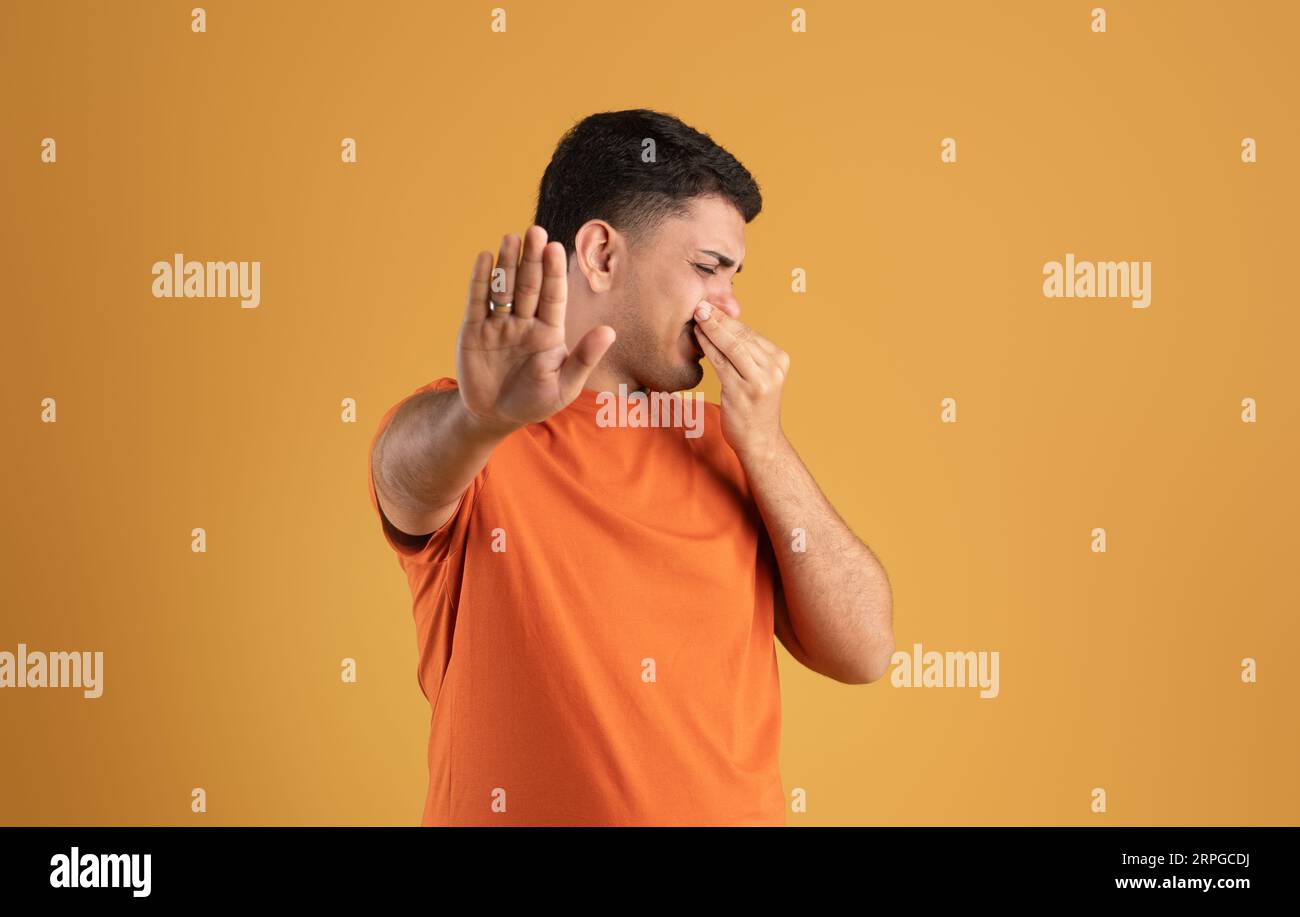 Un terribile concetto di odore. Uomo brasiliano che chiude il naso e FERMA I gesti, ripugnato da un odore sgradevole o da un profumo puzzolente Foto Stock