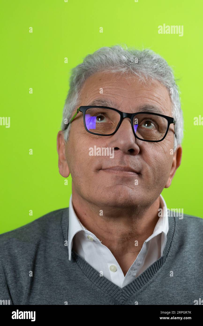 Ritratto di un anziano sorridente dai capelli grigi che guarda verso l'alto. Uomo caucasico maturo che indossa occhiali isolati su sfondo colorato Foto Stock