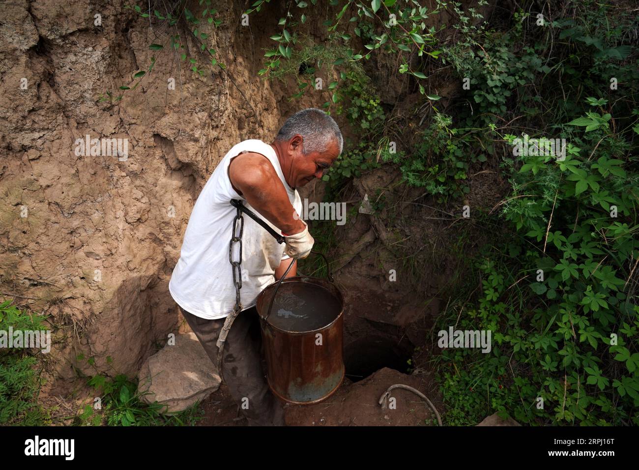 191122 -- YICHENG COUNTY, 22 novembre 2019 -- Un abitante del villaggio raccoglie acqua immagazzinata in una fossa di fango nel villaggio di Nanling della contea di Yicheng, nella provincia dello Shanxi della Cina settentrionale, 2 luglio 2019. Quando l'interruttore è stato tirato, l'acqua è fuoriuscita da 403 metri sotto. Il primo pozzo d'acqua profonda di Nanling Village è entrato in servizio la mattina presto d'inverno. In passato, il villaggio, che si estendeva attraverso i burroni dei monti Zhongtiao nella Cina settentrionale, si era affidato esclusivamente ai pozzi di fango per immagazzinare la sua preziosa acqua potabile per secoli. Perseguitati dalla paura della siccità, generazioni avevano sognato l'accesso diretto al bere Foto Stock