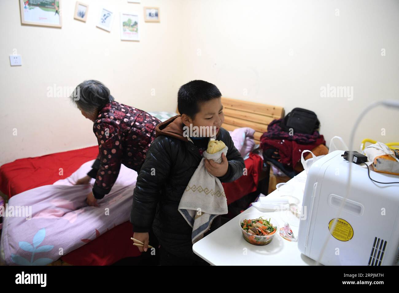 191214 -- HEFEI, 14 dicembre 2019 -- Un bambino ha un pasto in un ostello vicino al Children s Hospital di Hefei, provincia di Anhui, Cina orientale, 9 dicembre 2019. Vicino all'ospedale dei bambini di Hefei, c'è un edificio rosa a due piani, che viene affittato da un'organizzazione non governativa del benessere come ostello che fornisce camere gratuite a breve termine e auto-aiuto Love Kitchen per le famiglie colpite dalla povertà con bambini in cerca di cure mediche. Nella cucina dell'amore , acqua, elettricità, riso, farina, cereali, olio e utensili da cucina sono tutti disponibili gratuitamente. Al fine di rendere la Love Kitchen più scorrevole, genitori Foto Stock