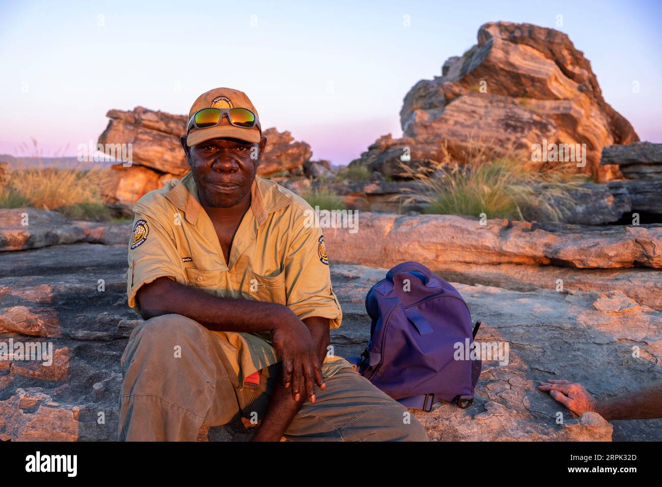 Guida turistica indigena al tramonto sulla cima della roccia di Ubirr nel Parco Nazionale di Kakadu nel territorio del Nord. Guida indigena, James Dempsey lavora per i Njanjma Rangers. Foto Stock