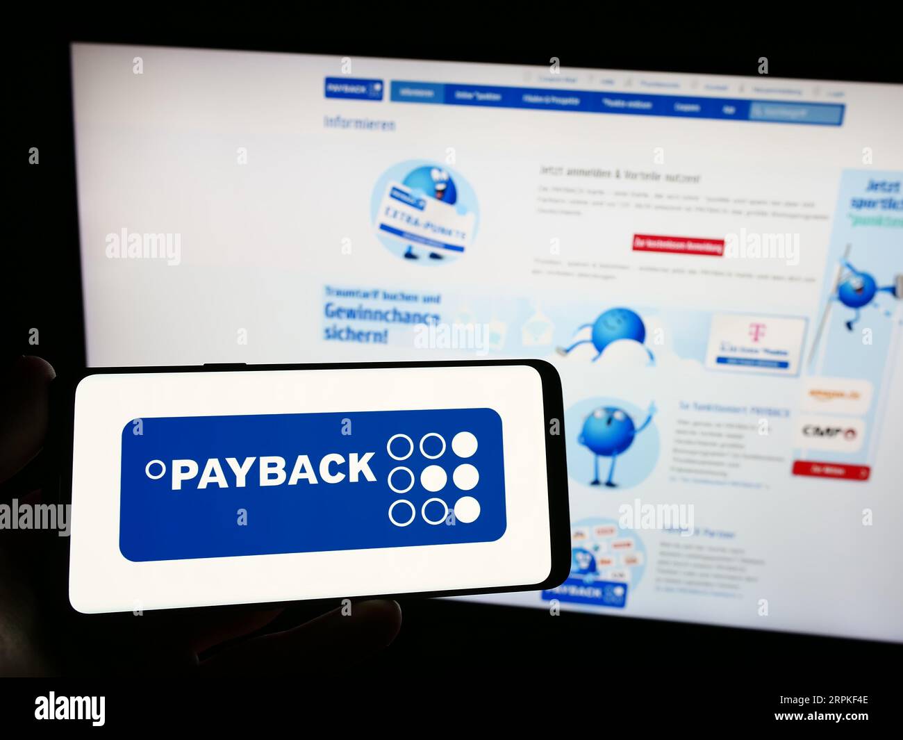 Persona che possiede uno smartphone con il logo della società tedesca di gestione della fidelizzazione Payback GmbH sullo schermo davanti al sito Web. Concentrarsi sul display del telefono. Foto Stock